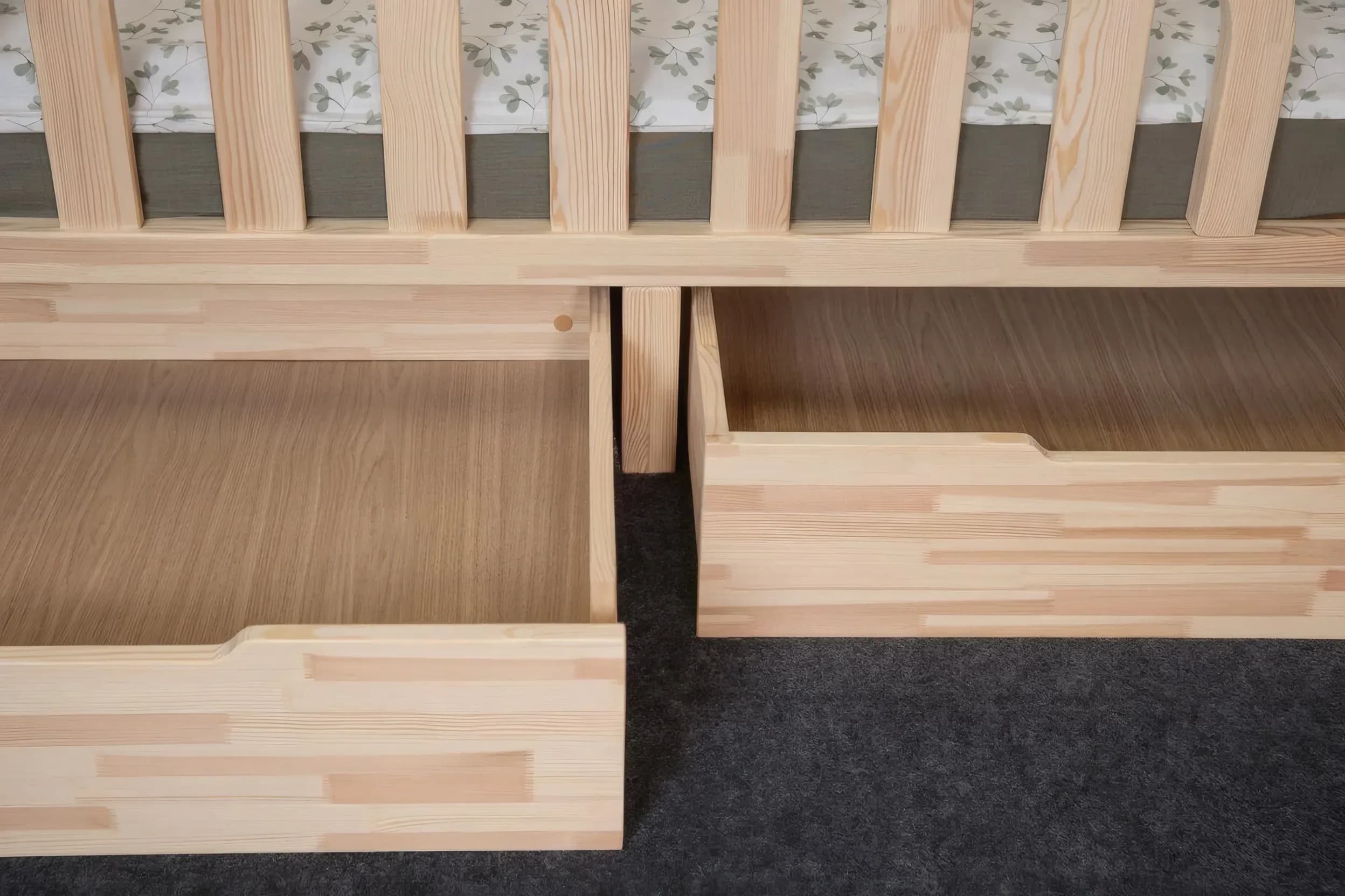 Nahaufnahme von zwei offenen Holzschubladen unter dem Bett