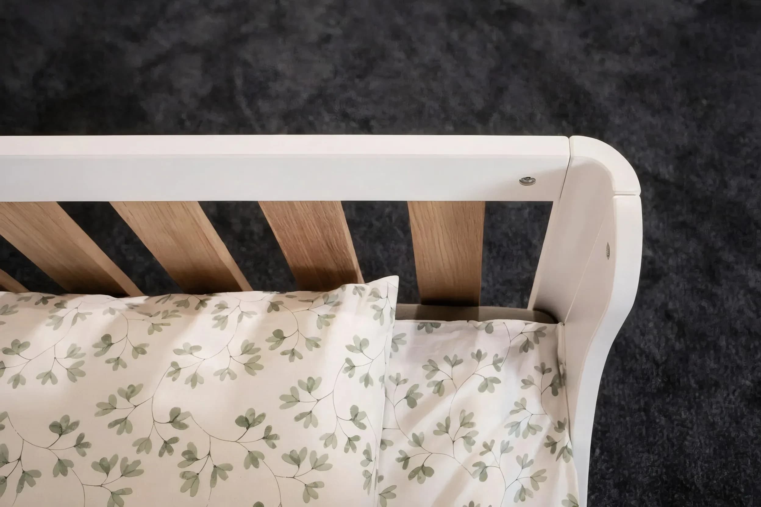 Close-up of the rounded white end panel of the two-tone bed with bedding