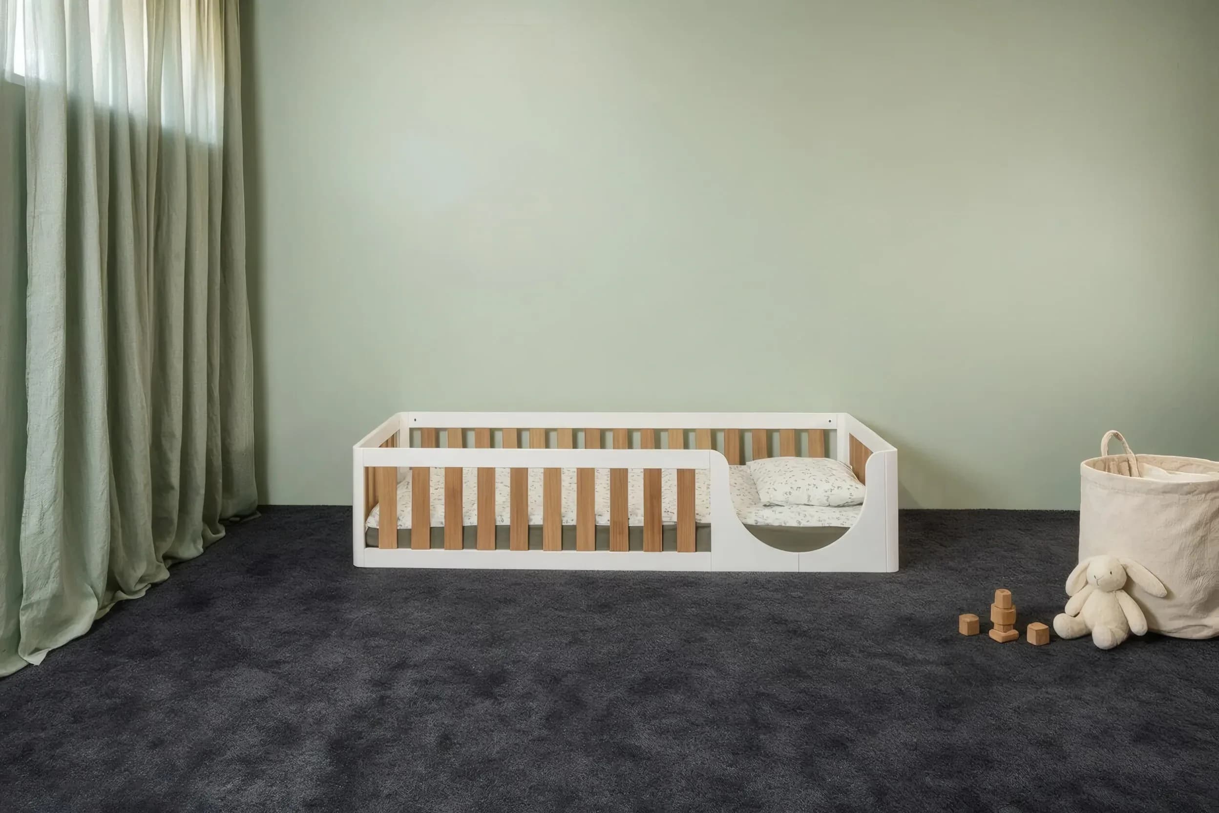 Low white floor bed with oak veneer bars in a nursery, front view
