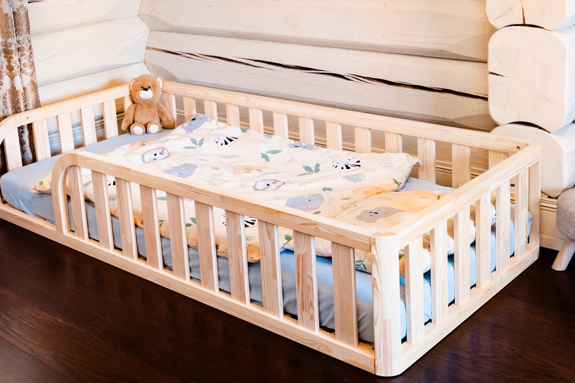 Lit de sol Montessori en bois naturel avec entrée arrondie et bords de protection pour la chambre d'enfant