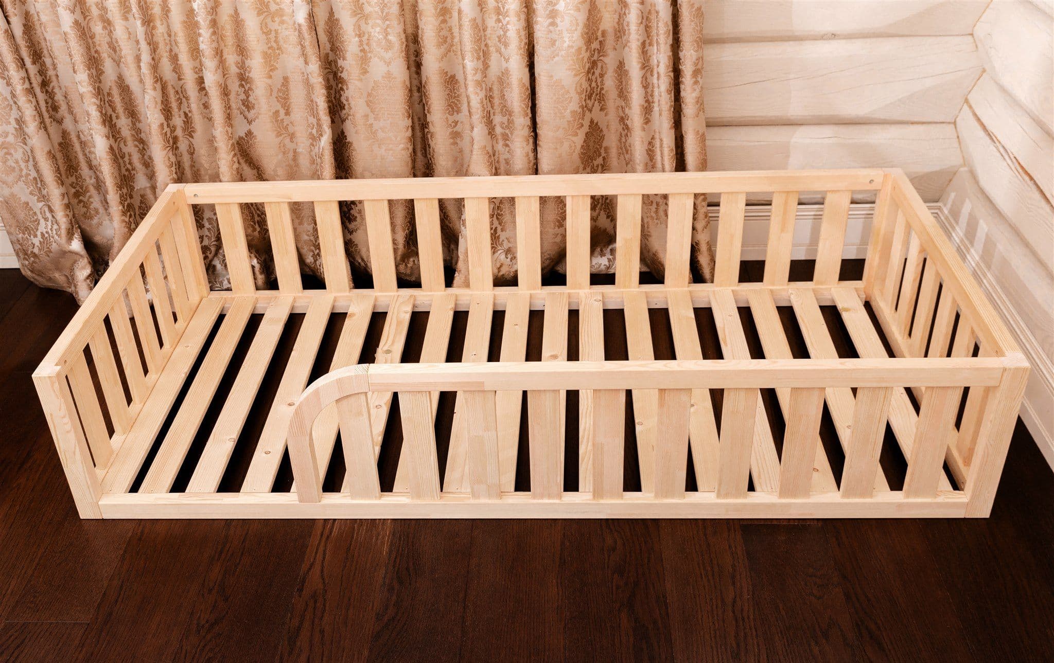 Lit de sol Montessori en bois naturel avec entrée arrondie et bords de protection pour la chambre d'enfant