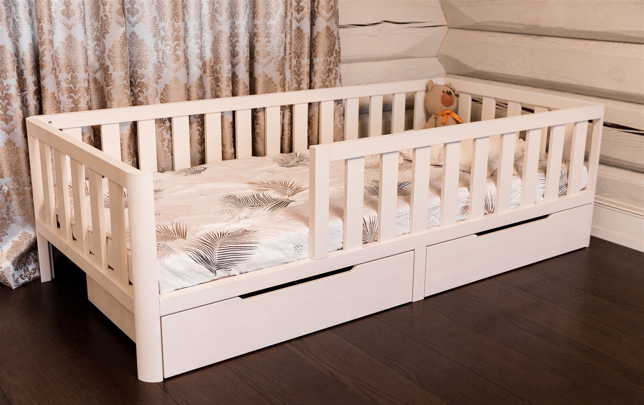 White solid pine wood Montessori toddler floor bed with protective guardrails, rounded corners, and two under-bed storage drawers
