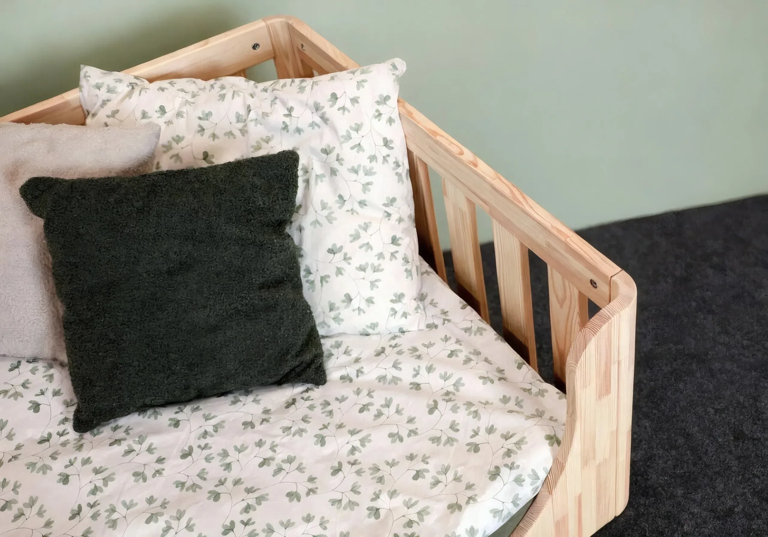Primer plano de la esquina redondeada de la cama de suelo con ropa de cama y almohadas