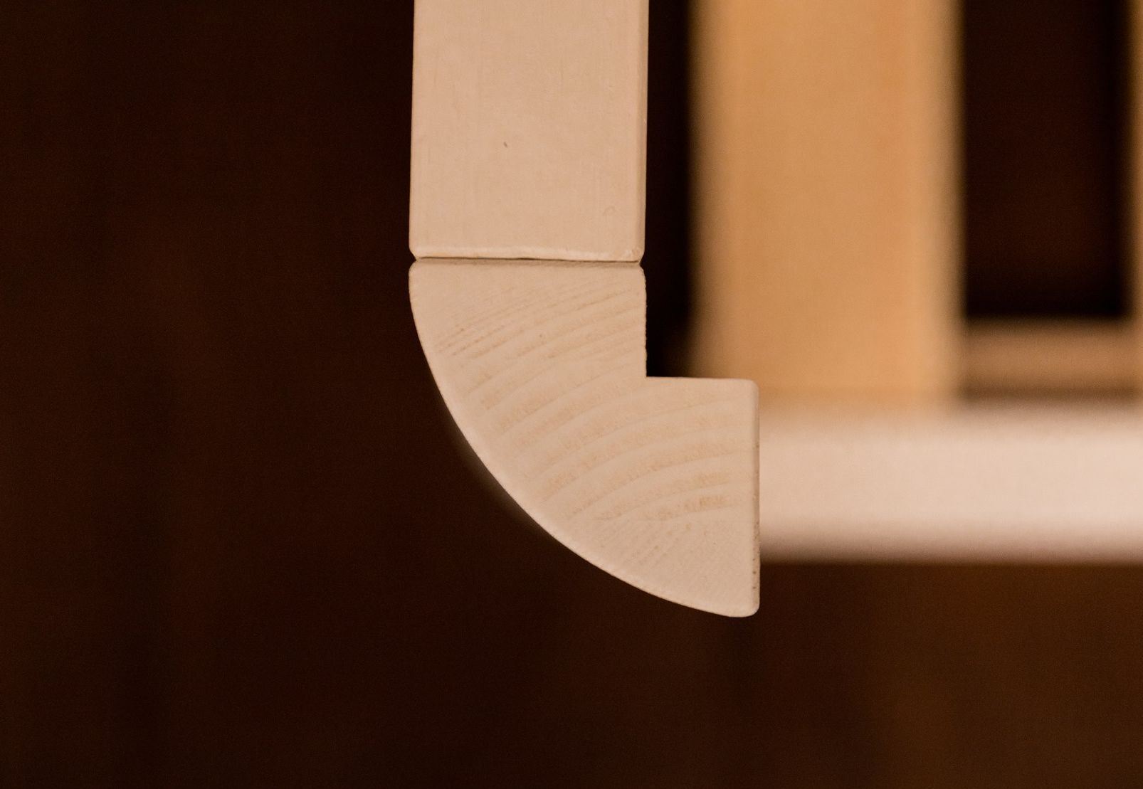 Primer plano de una esquina exterior redondeada de una cama Montessori blanca
