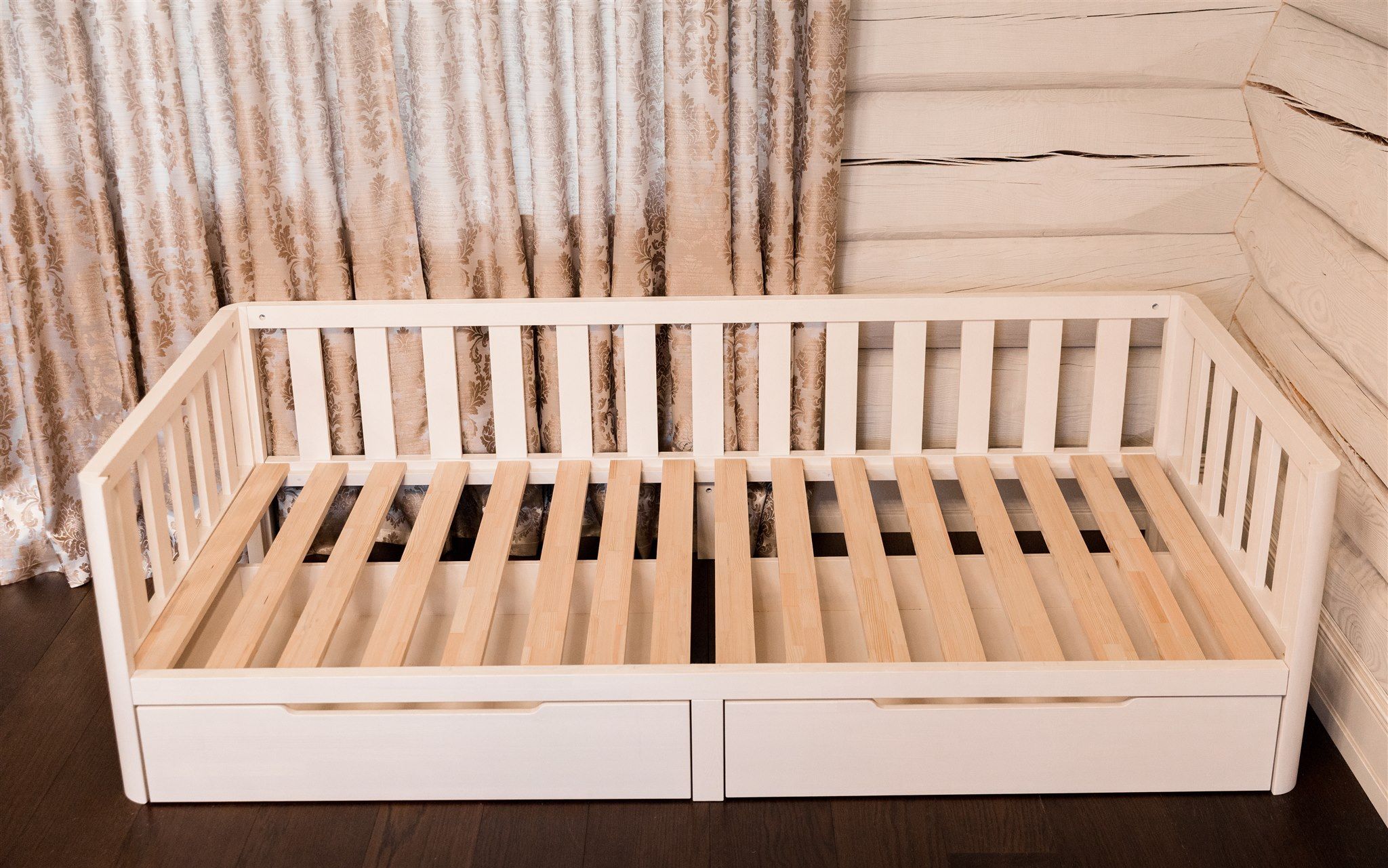 Letto Montessori bianco con fronte aperto e doghe in legno, vista angolata