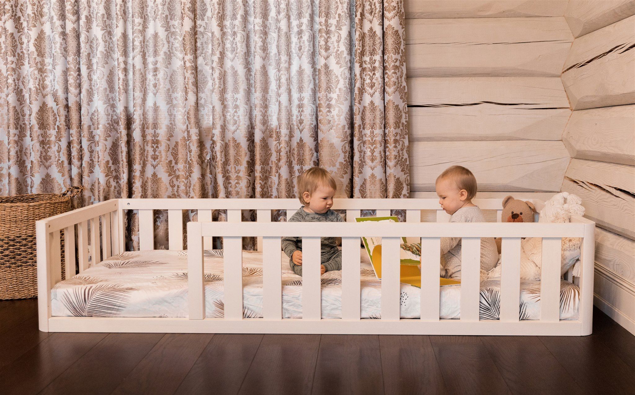 Dos niños jugando en una cama Montessori blanca con barandillas