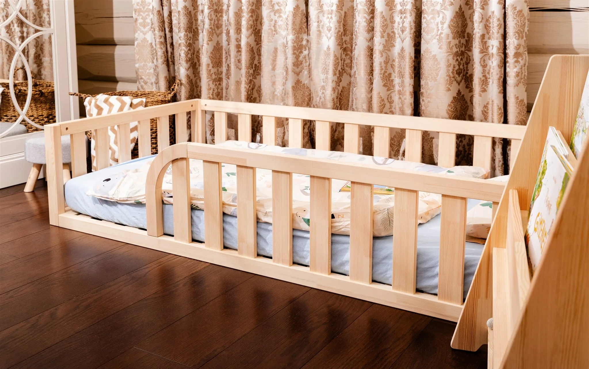 wooden Montessori toddler floor bed with protective safety guardrails on dark floor
