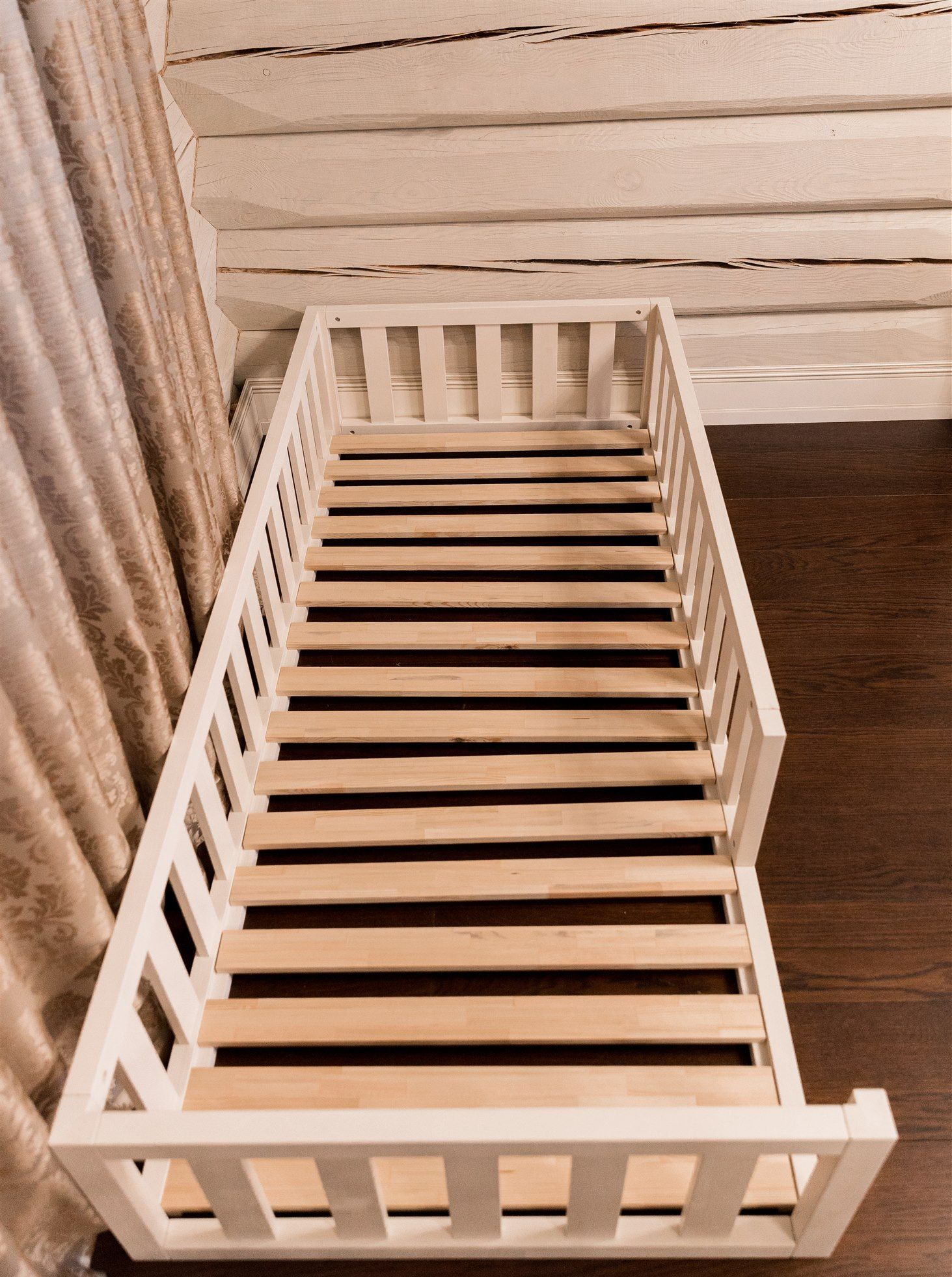 Cama Montessori blanca con listones de madera, vista superior
