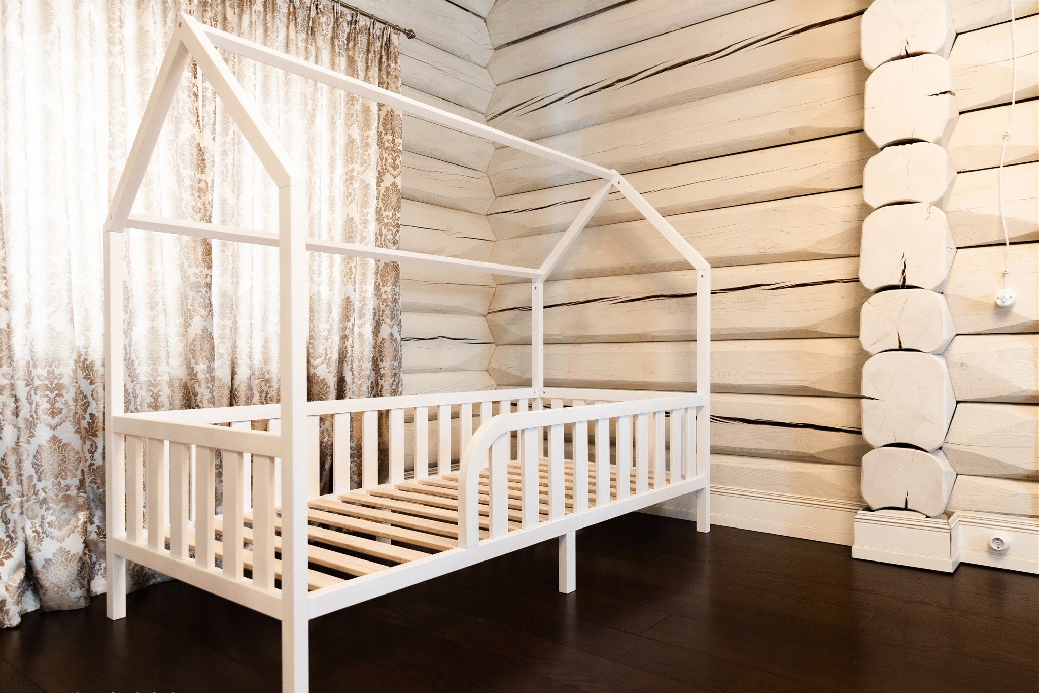 Cama casita blanca sobre patas con entrada redondeada y lamas de madera
