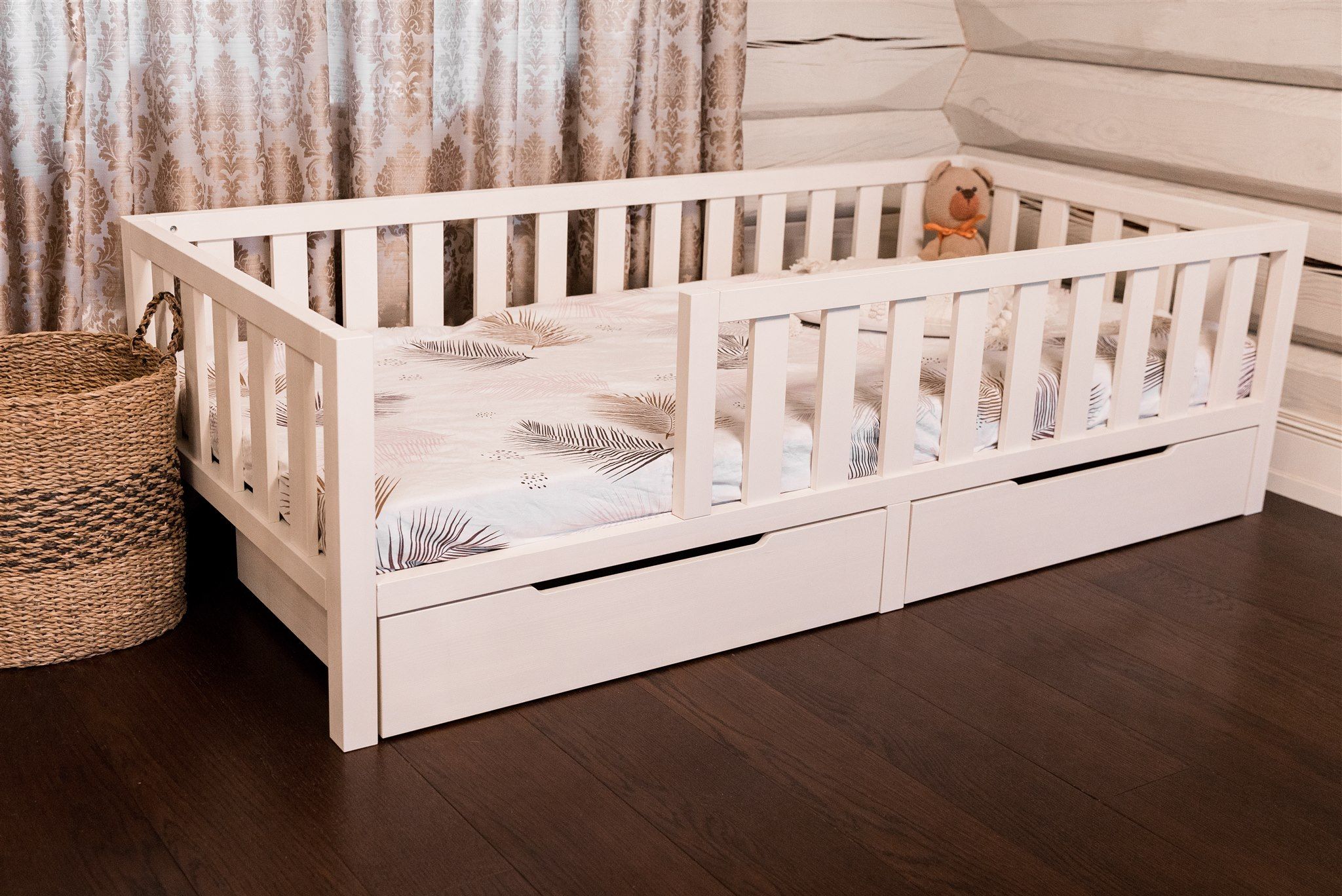 Cama Montessori blanca con dos cajones y barandillas, vista en ángulo