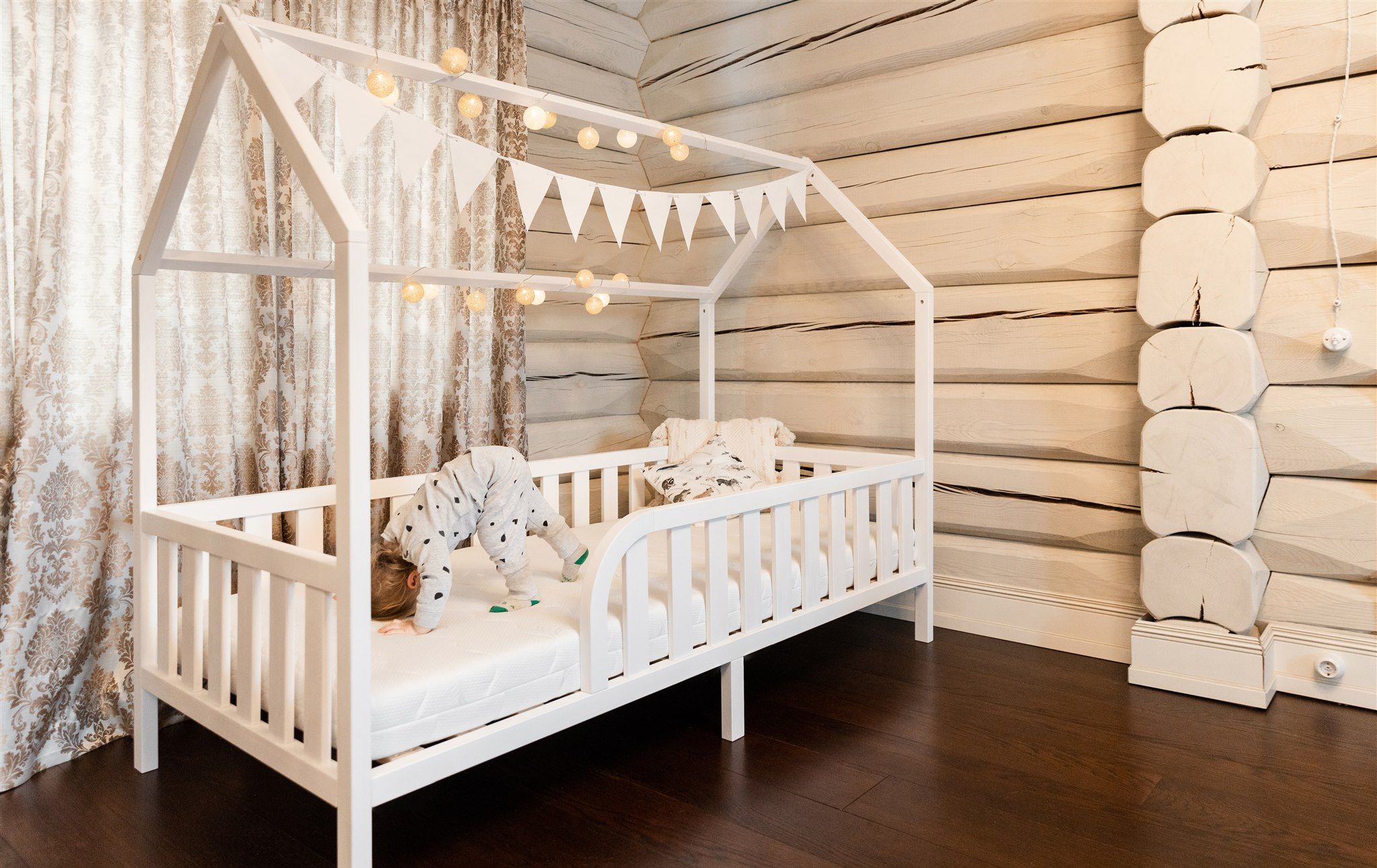 Letto a casetta Montessori bianco su gambe con ingresso arrotondato e materasso, vista angolare