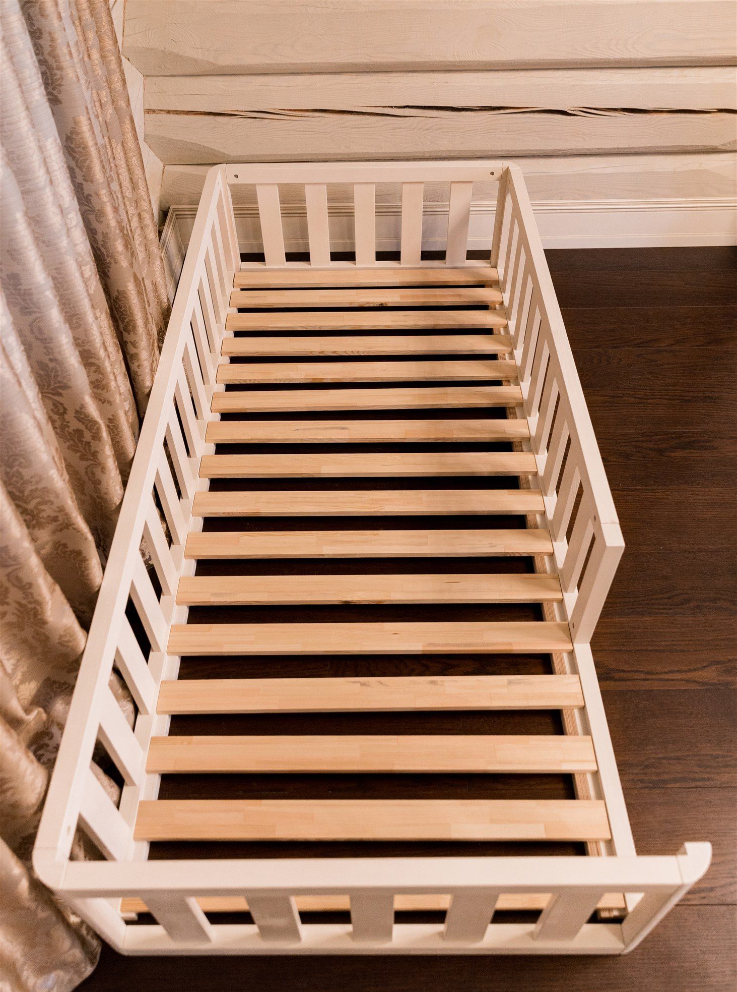Lamas de madera natural en la cama Montessori blanca, vista desde los pies